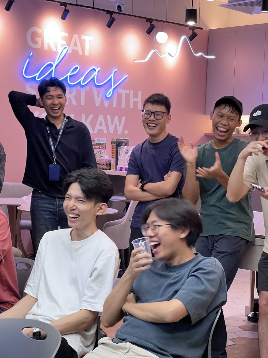 Teammates laughing while watching entries in an AI video challenge at the office