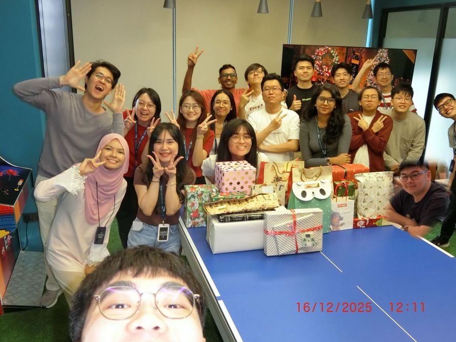 The team gathered around a ping-pong table piled with wrapped presents at the Christmas gift exchange