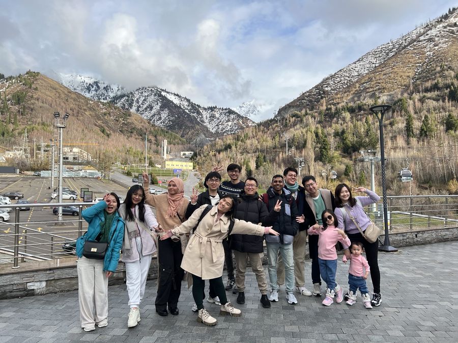 The team on a company trip in Almaty, Kazakhstan, with snow-capped mountains behind